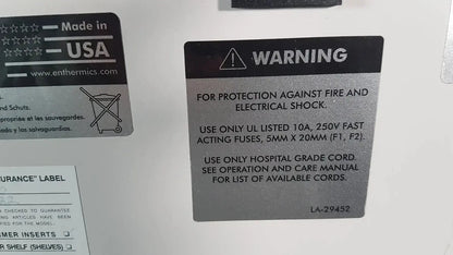 Black warning label with white text and caution symbol on the back of enthermics blanket warming cabinet dc250 detailing electrical safety instructions