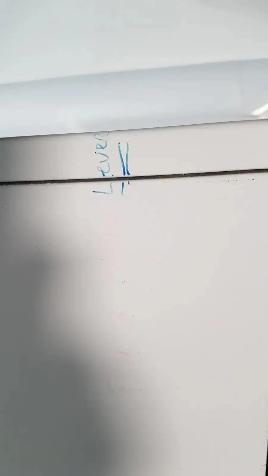 White wall with blue handwritten text and dark line on the back of enthermics blanket warming cabinet dc250