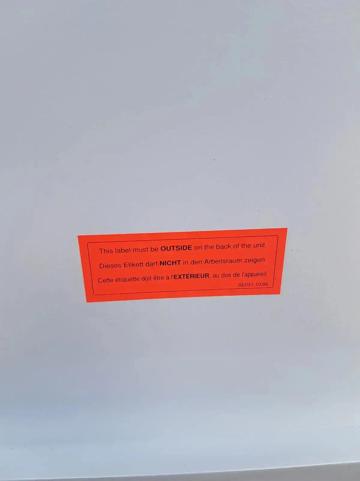 Orange rectangular label with black multilingual text on the back of erlab captair bio chem filtair ductless fume enclosure