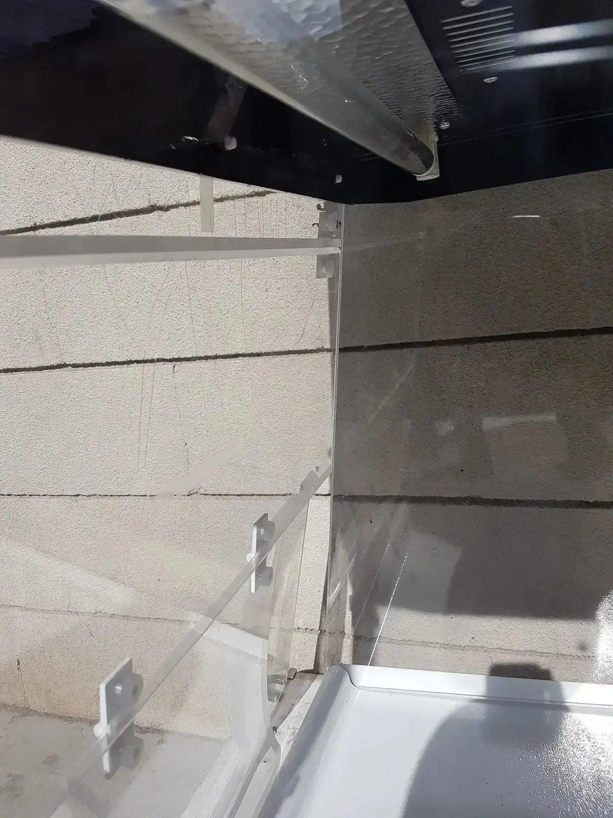 Black metal frame with silver hardware securing glass panels on beige wall of erlab captair bio chem filtair hood
