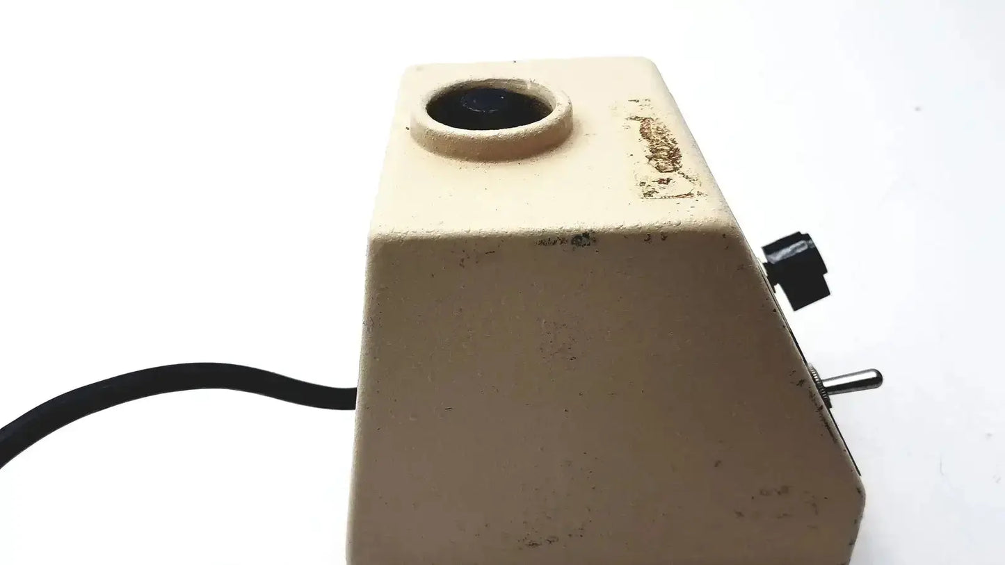 Beige vintage slide projector with circular lens and black knobs shown alongside fisher scientific vortex genie mixer shaker