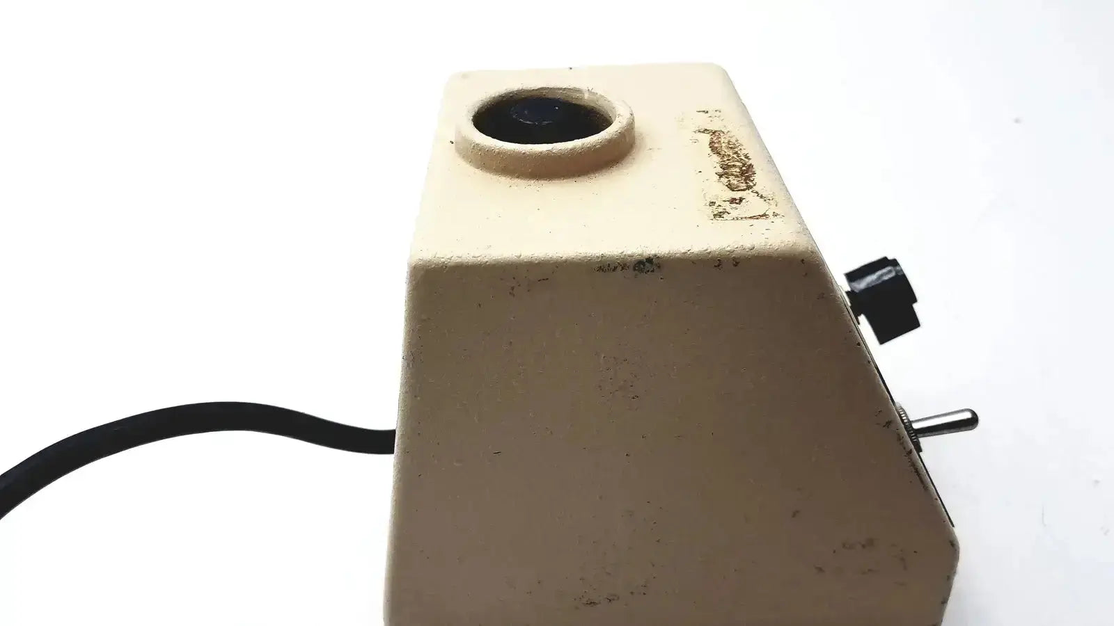 Beige vintage slide projector with circular lens and black knobs shown alongside fisher scientific vortex genie mixer shaker