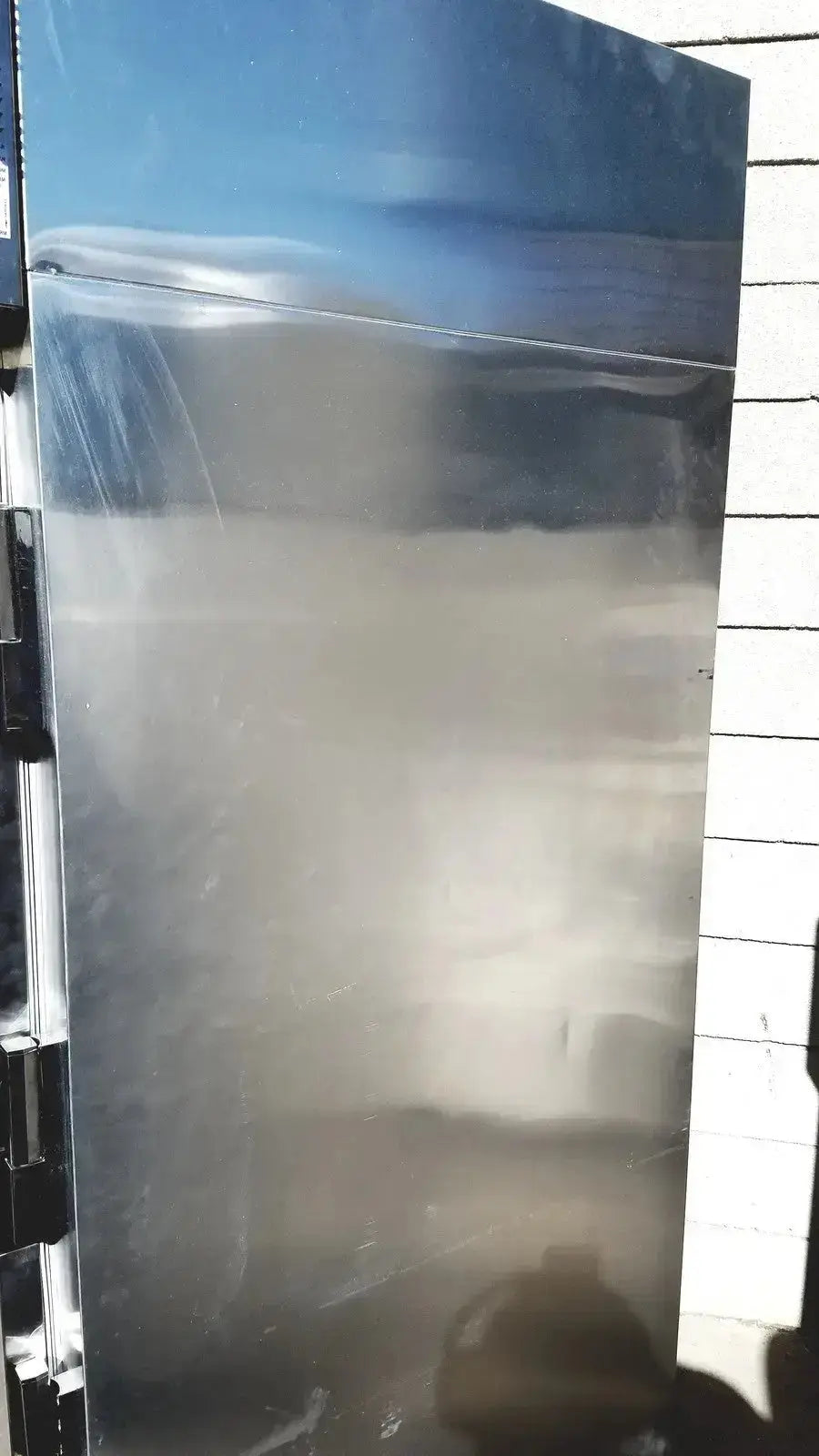A tall stainless steel isotemp laboratory freezer refrigerator door with reflective surface and visible seams