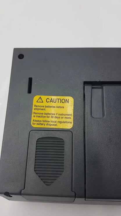 Black plastic back side of fluke 1620a dewk digital thermometer-hygrometer with yellow caution label and battery compartment