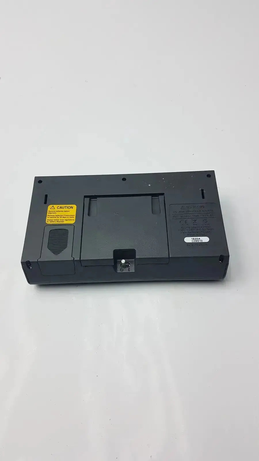 Black plastic laptop docking station with yellow caution label and port on the back of fluke 1620a dewk digital thermometer-hygrometer