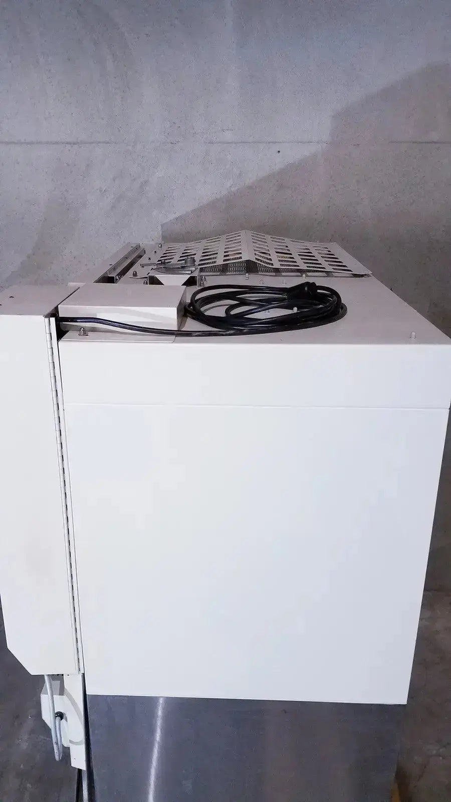 White industrial-grade paper shredder with perforated top and coiled black power cord for biological safety cabinet use