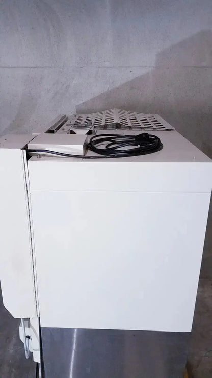 White industrial-grade paper shredder with perforated top and coiled black power cord for biological safety cabinet use