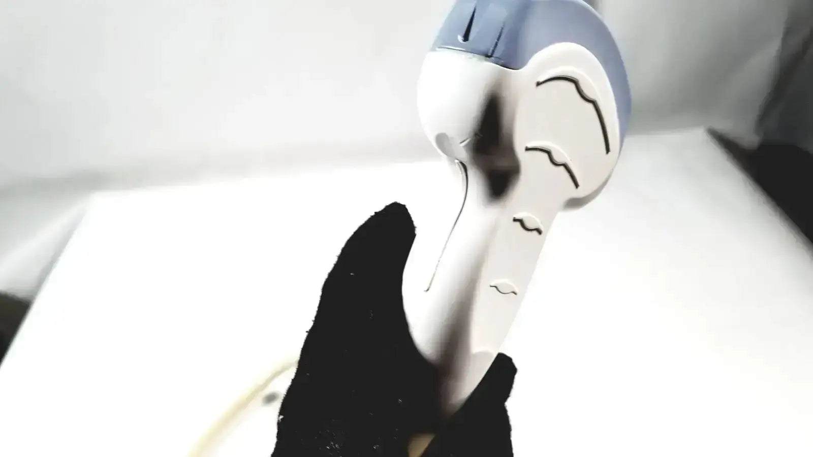 White and blue handheld hair dryer with stylized face design resembling convex array ultrasound transducer probe