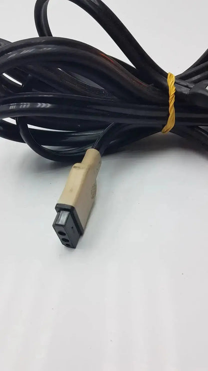 Black coiled GE cable with beige and black connector secured by yellow twist tie for hospital surplus medical equipment use