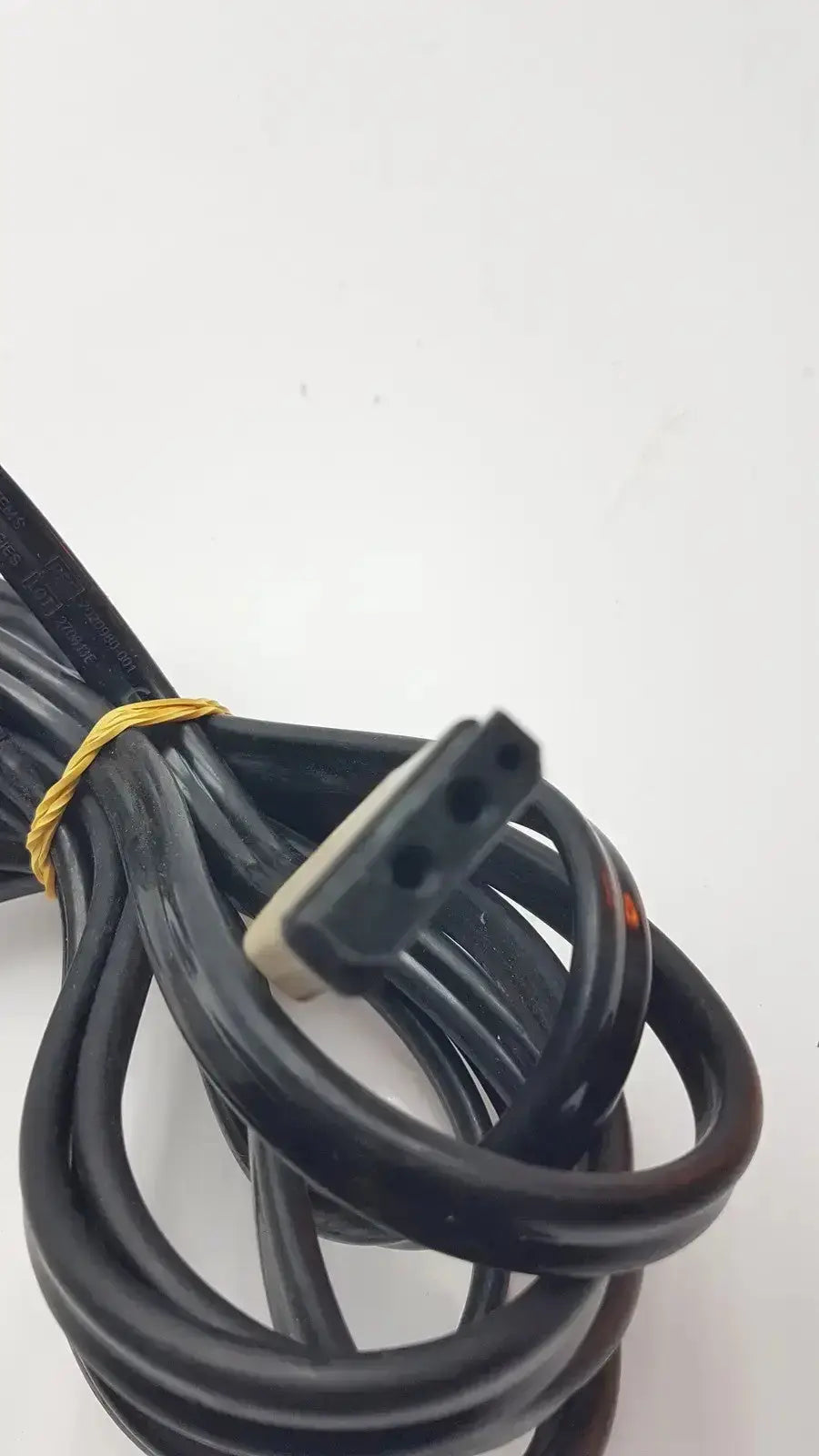 Black coiled GE cable with rectangular three-hole connector and beige housing tied by yellow rubber band for medical equipment
