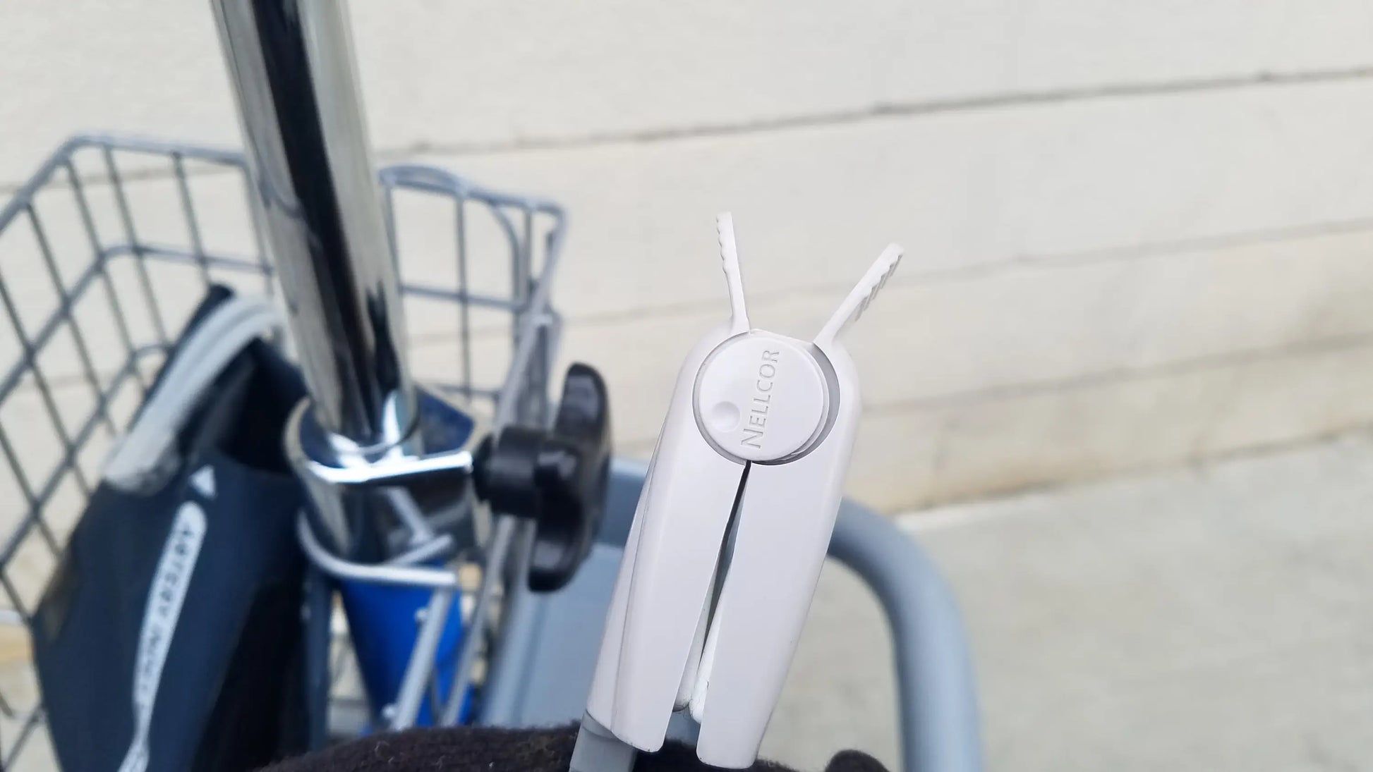 White plastic bicycle lock with two prongs and circular branded plate for reuse medical equipment on dinamap procare dpc monitor