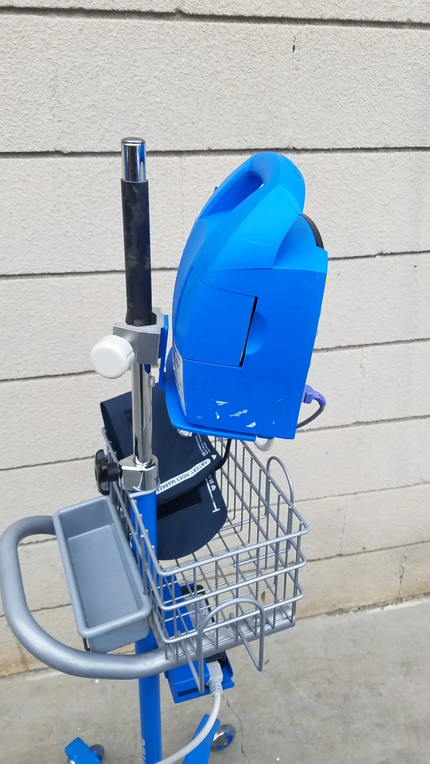 Blue plastic GE Dinamap ProCare DPC 400 vital signs monitor on mobile cart with metal basket gray tray medical equipment