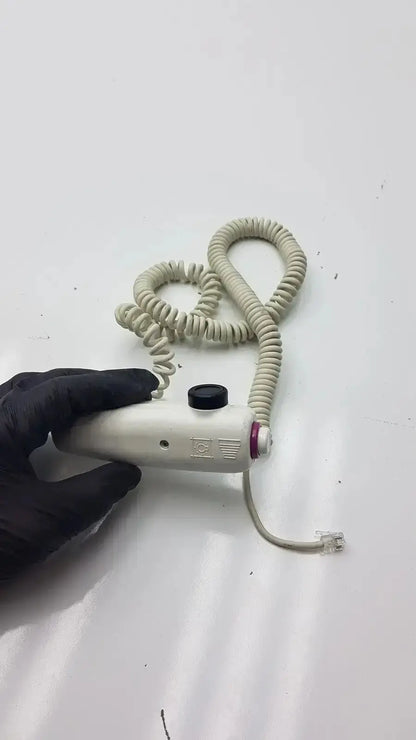 Beige coiled cable dragonfly hand switch with black button and red accent for precise handheld control