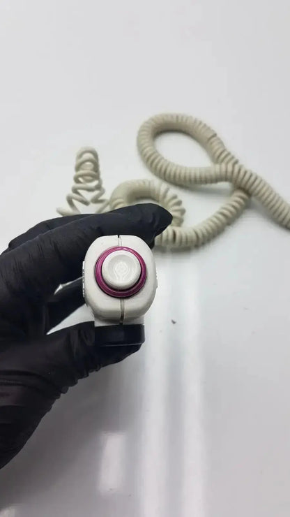 White and magenta dragonfly hand switch with textured grip held in black-gloved hand showing ergonomic design