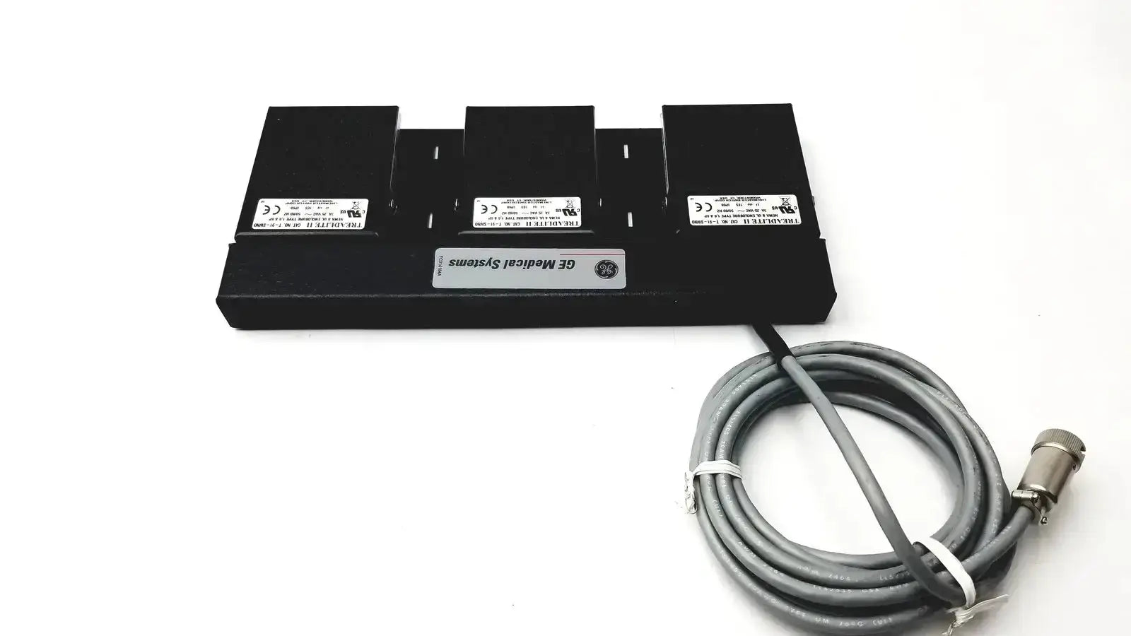 Black ge medical systems battery charger with three slots and coiled gray power cable for systems footswitch use