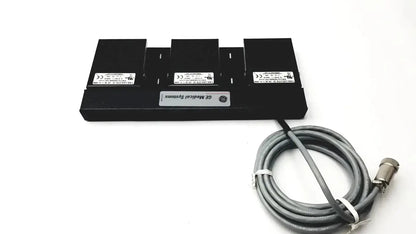 Black ge medical systems battery charger with three slots and coiled gray power cable for systems footswitch use