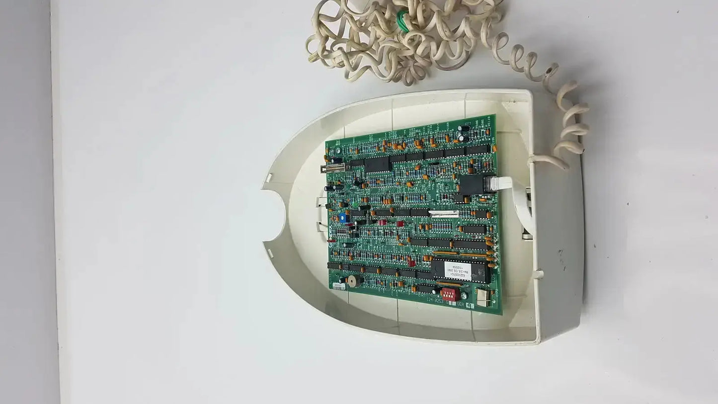White plastic housing with green circuit board and beige coiled cord in gendex 765dc xray remote control panel back view