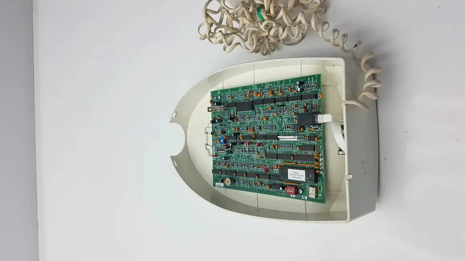 White plastic housing with green circuit board and beige coiled cord in gendex 765dc xray remote control panel back view