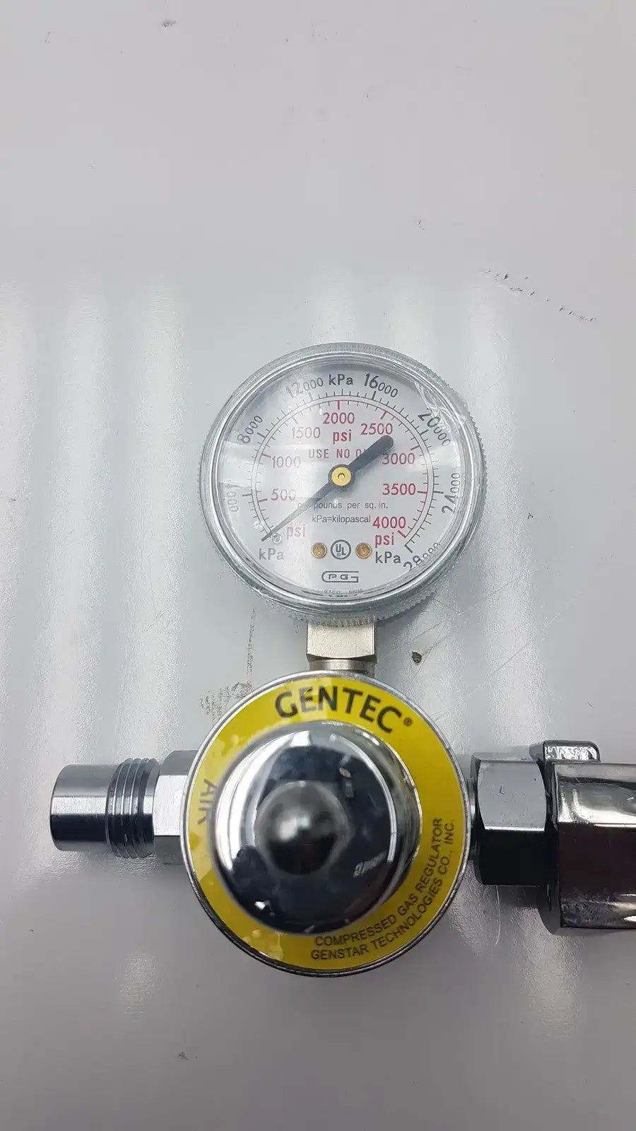 Gentec CGA950 compressed air regulator with silver metallic body yellow label and gauge displaying psi and kpa measurements