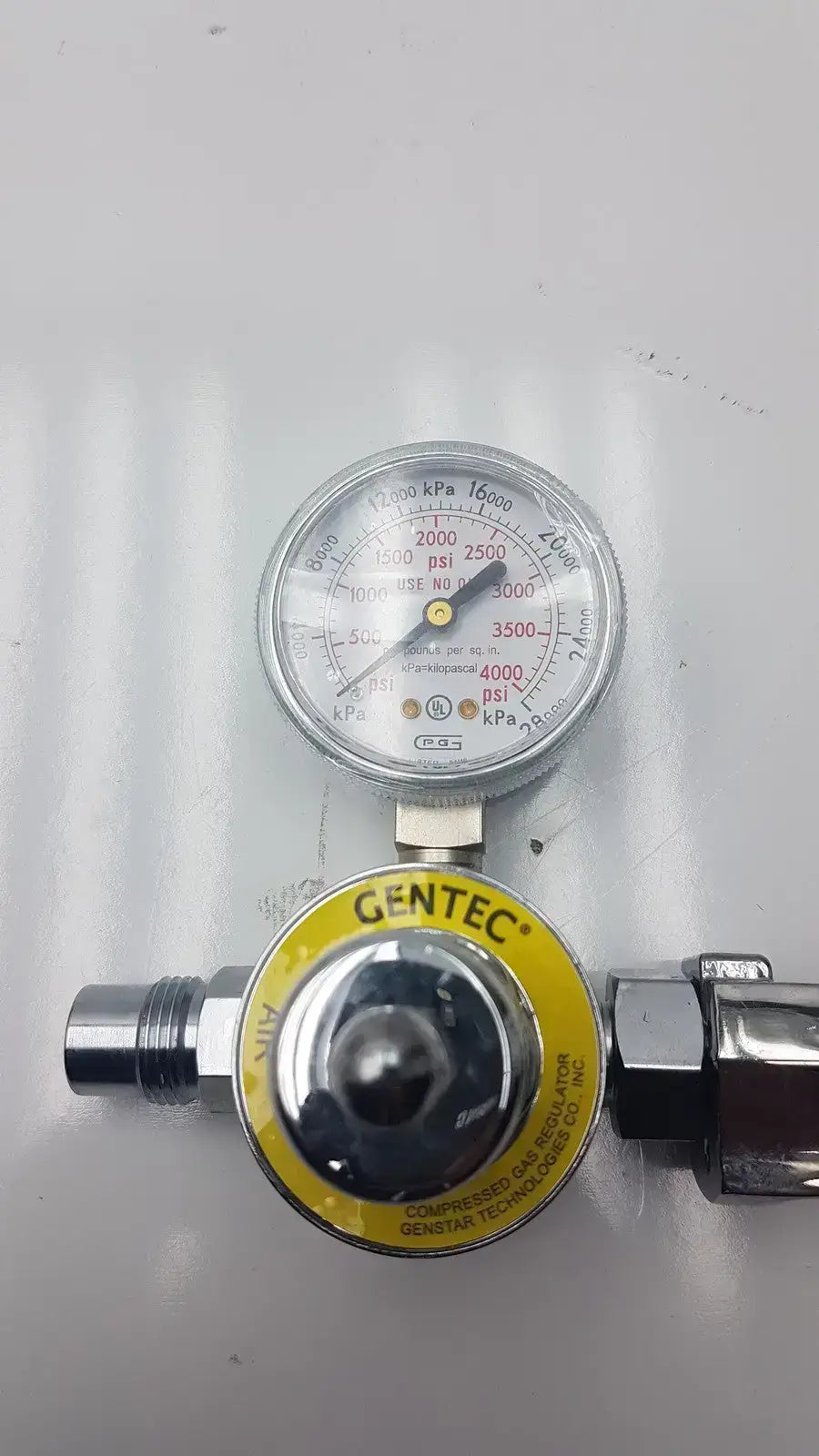 Gentec CGA950 compressed air regulator with silver metallic body yellow label and gauge displaying psi and kpa measurements