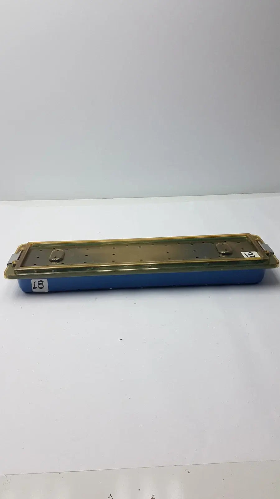 Blue plastic gyrus mra-gt slimline sterilization tray with gold metal lid featuring holes and two latches for medical equipment reuse