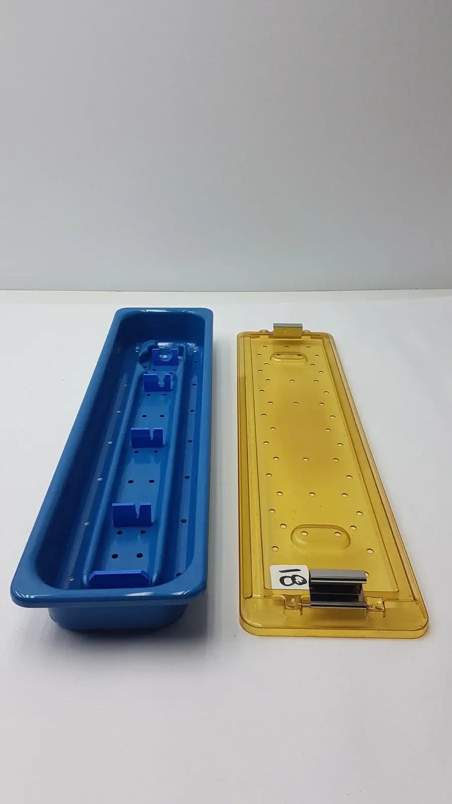 Blue and yellow plastic slimline sterilization tray with perforated surfaces and molded compartments for medical equipment reuse