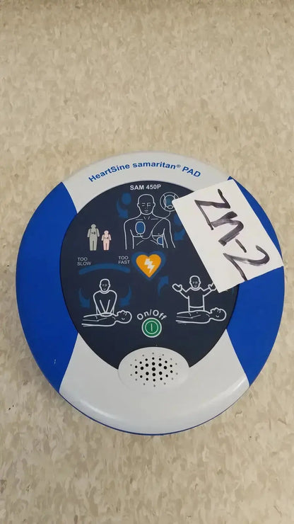 Blue and white heartsine samaritan pad 450p automated external defibrillator with instructional diagrams on circular face