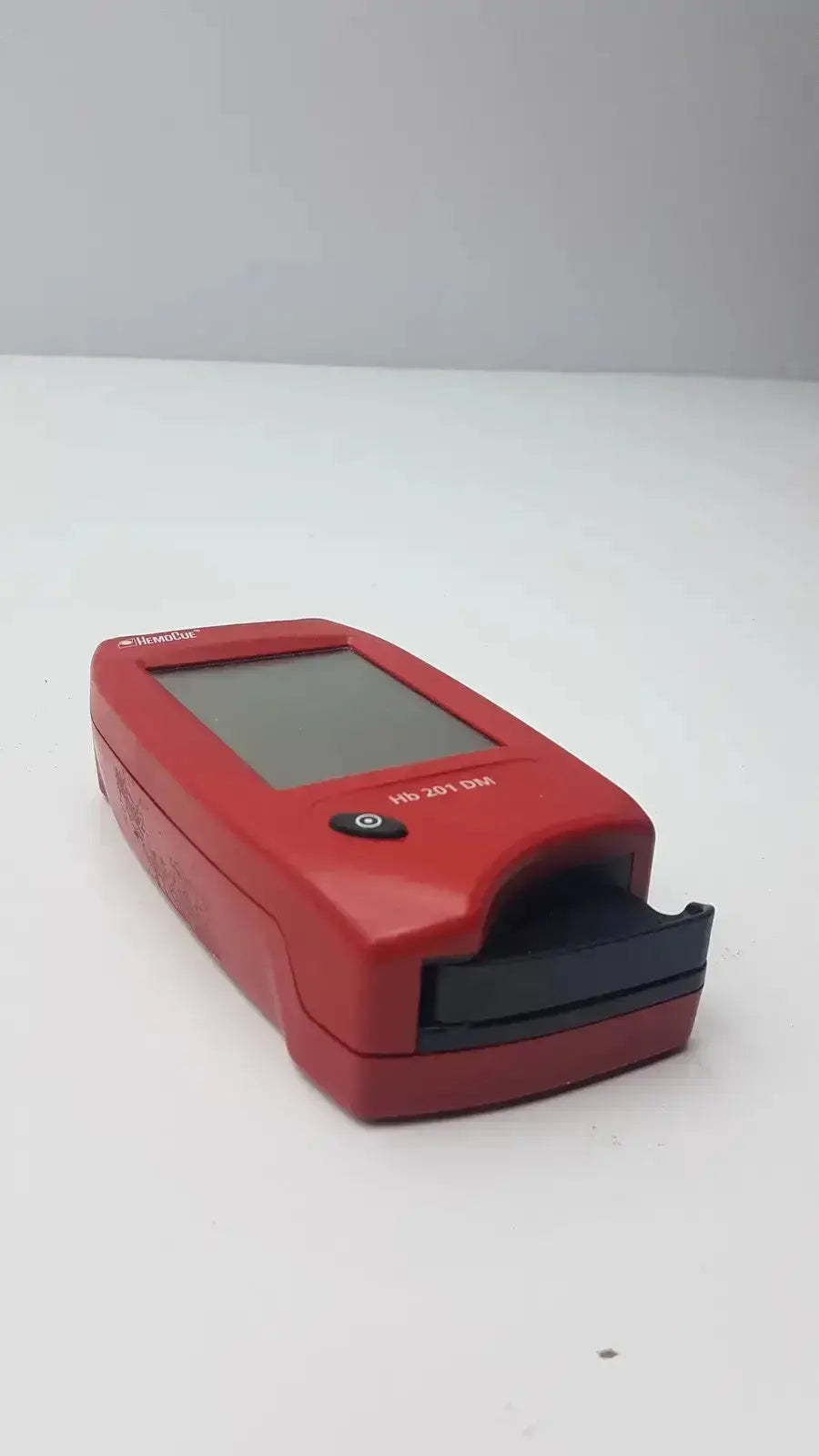 Red handheld biomedical evaluation device hemoCue hb 201 DM with rectangular screen and black button for hospital surplus reuse medical