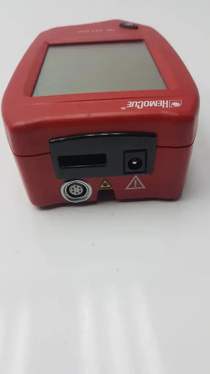 Red hemocue handheld blood glucose analyzer with square screen and black ports for biomedical evaluation and hospital surplus reuse medical