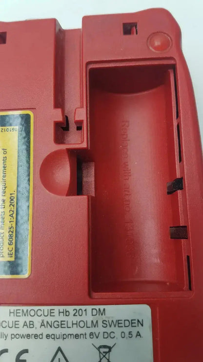 Red plastic hemocue hb 201 dm battery charger with molded compartments and yellow label for biomedical evaluation