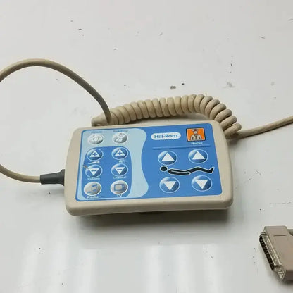 Beige plastic Hill-Rom patient hand control with blue interface and coiled cable for bed 16646202 use