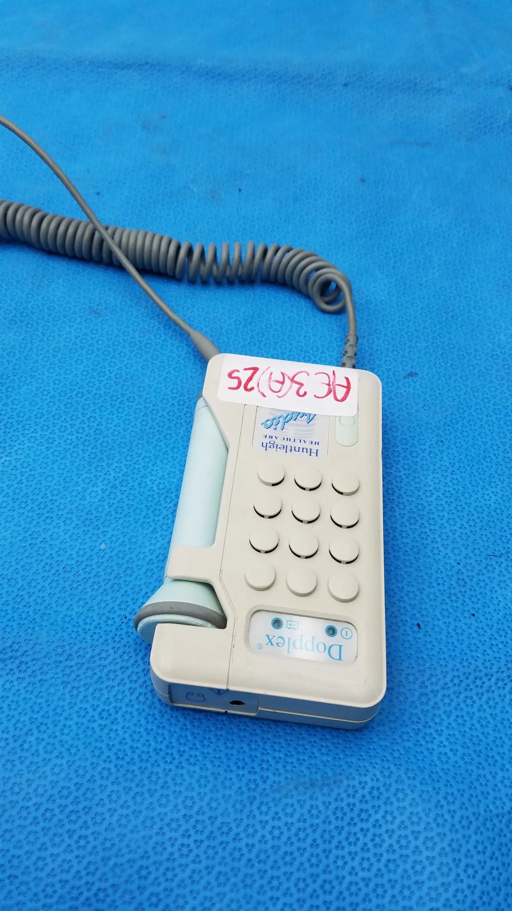 Beige huntleigh dopplex d920 handheld doppler with gray coiled cable and white label used in medical equipment by smiths medical