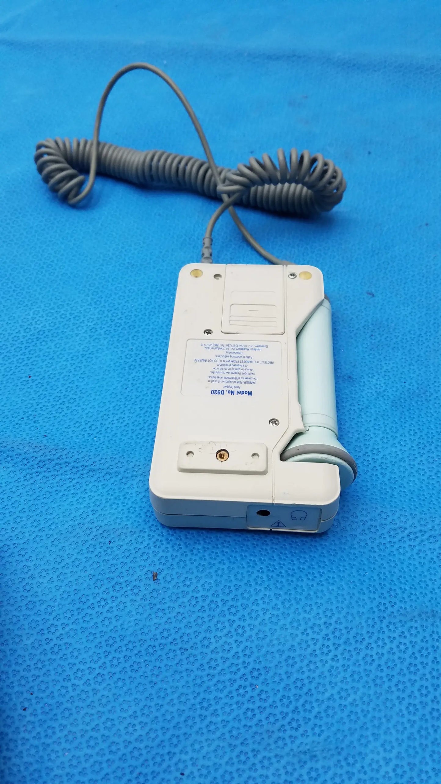 White plastic huntleigh dopplex d920 handheld doppler with coiled gray cable and light blue handle for medical equipment use
