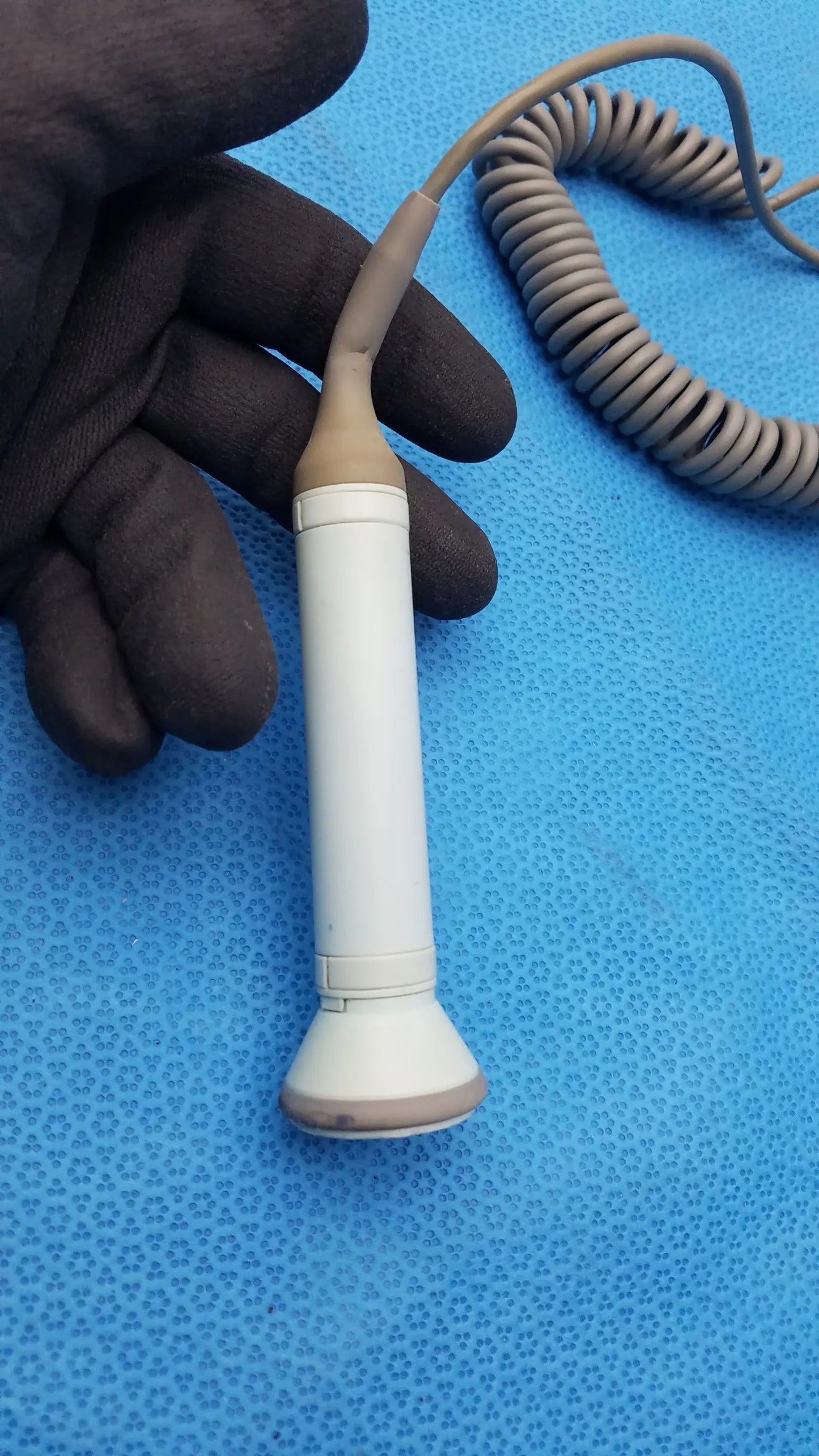 White and beige Huntleigh Dopplex D920 handheld Doppler ultrasound transducer with coiled gray cable medical equipment