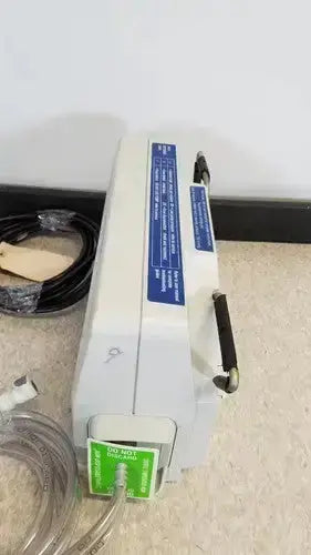 White medical infusion vp5000 dvt pump by Huntleigh with blue labeling black handle and green warning stickers on front