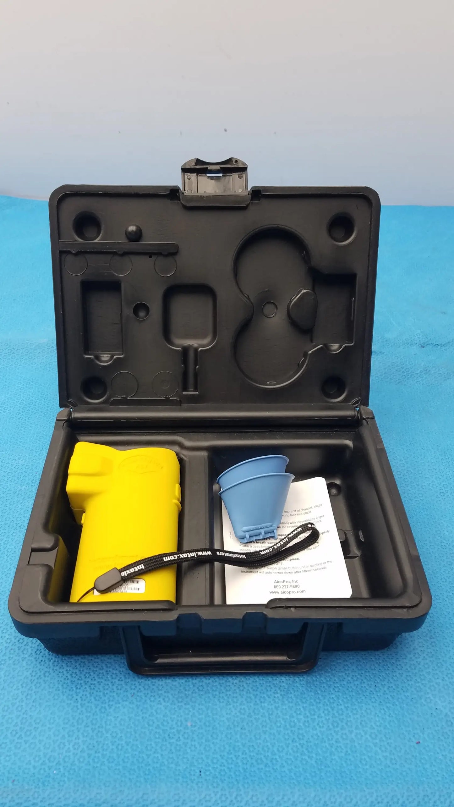 Yellow handheld defibrillator with black wrist strap inside black molded case for medical equipment by Smiths Medical
