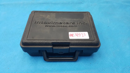 Black plastic carrying case embossed intoximeters inc with white label code ae36023 for portable handheld medical equipment