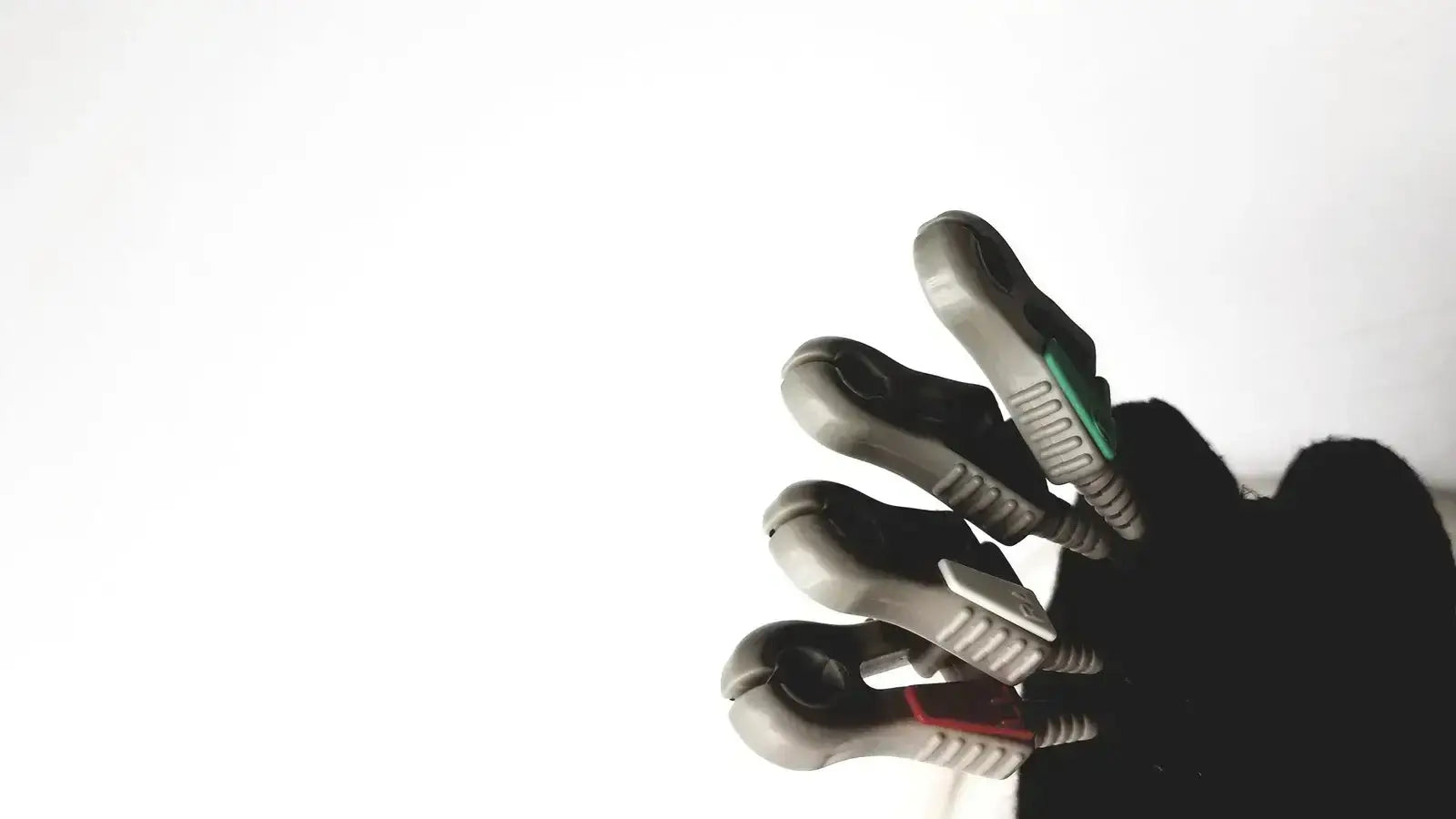 Gray and black robotic hand with textured grip surfaces and colored accents holding invivo 9240a ecg lead wires
