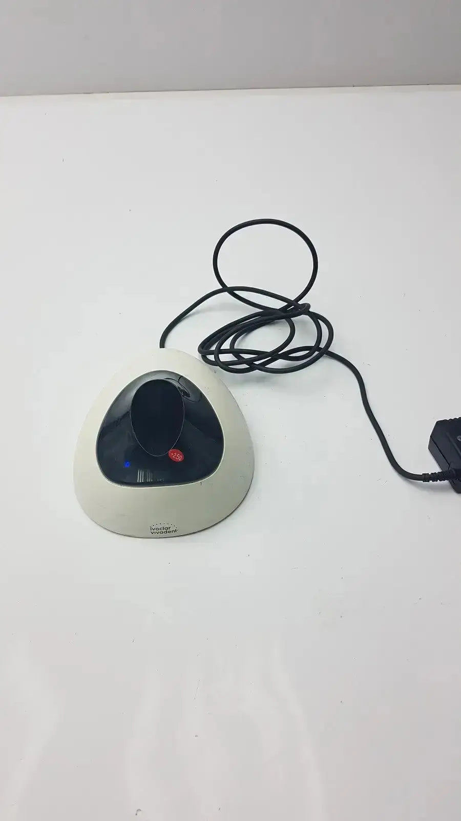 Cream-colored triangular-shaped computer mouse with black curved top and red button connected to ivoclar vivadent bluephase g2 docking stand