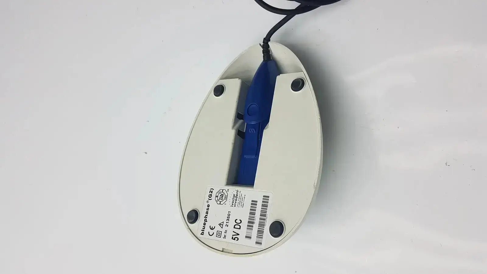 White plastic computer mouse with blue scroll wheel and black cord showing logitech brand name on underside for ivoclar vivadent bluephase g2 docking stand