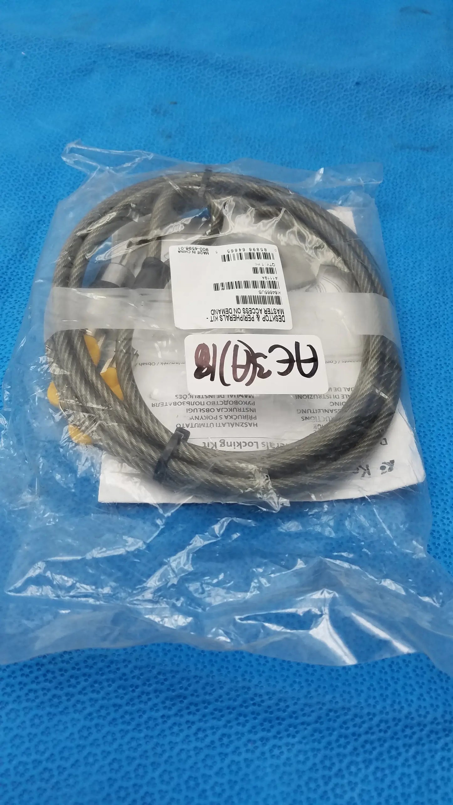 A coiled dark gray steel cable with yellow end fittings in clear plastic packaging for kensington desktop lock kit used medical equipment for sale