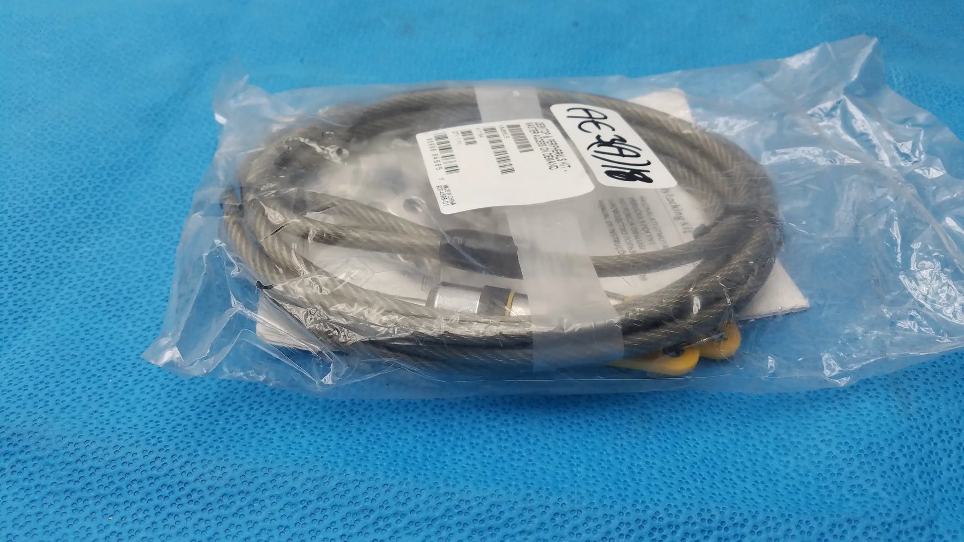 Gray braided steel cable with yellow connectors and clear plastic label packaging in kensington locking kit for pre owned medical equipment sale