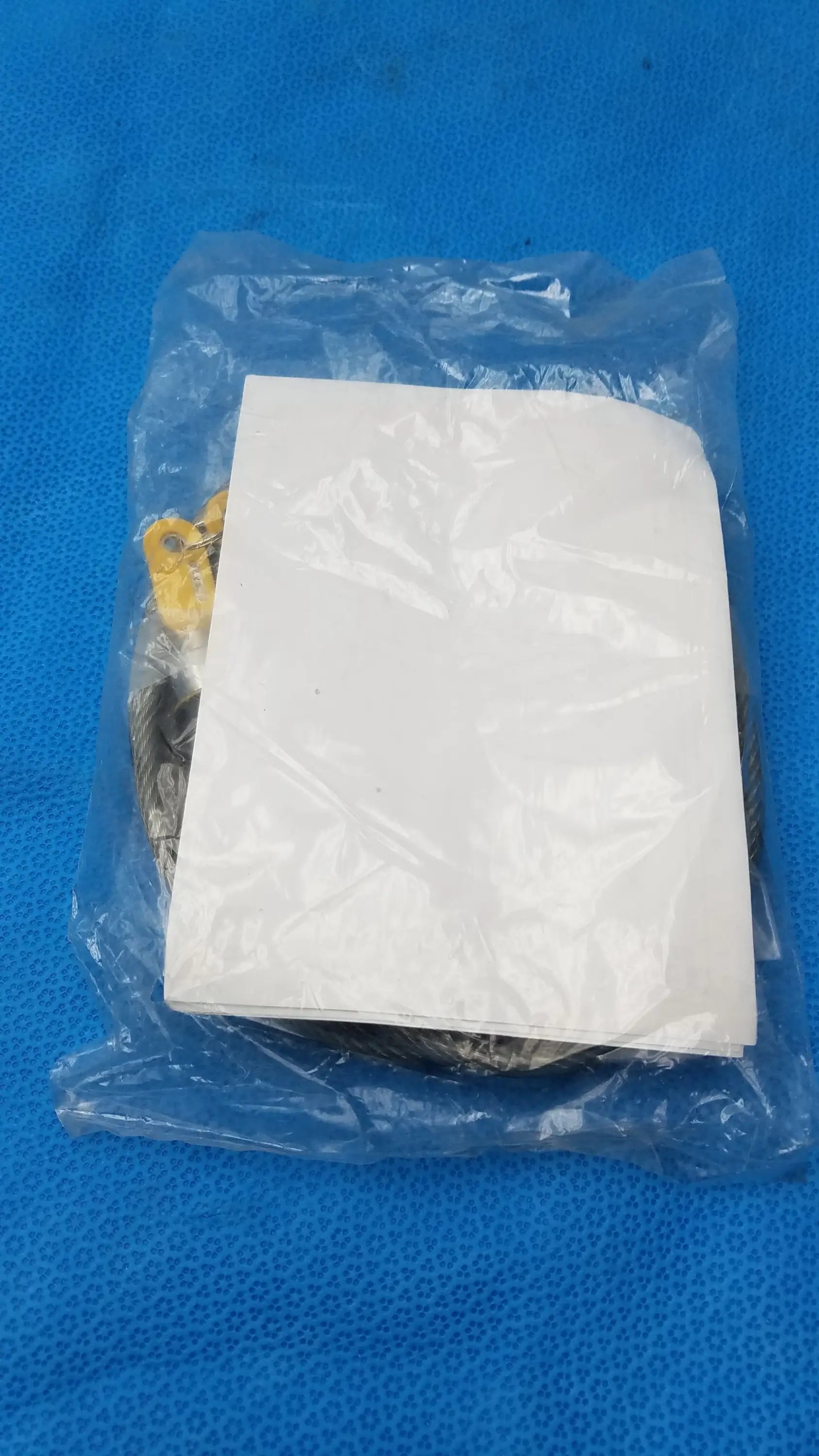A white paper insert inside a clear plastic bag partially obscures yellow and metallic parts of the kensington locking kit for pre owned medical equipment use