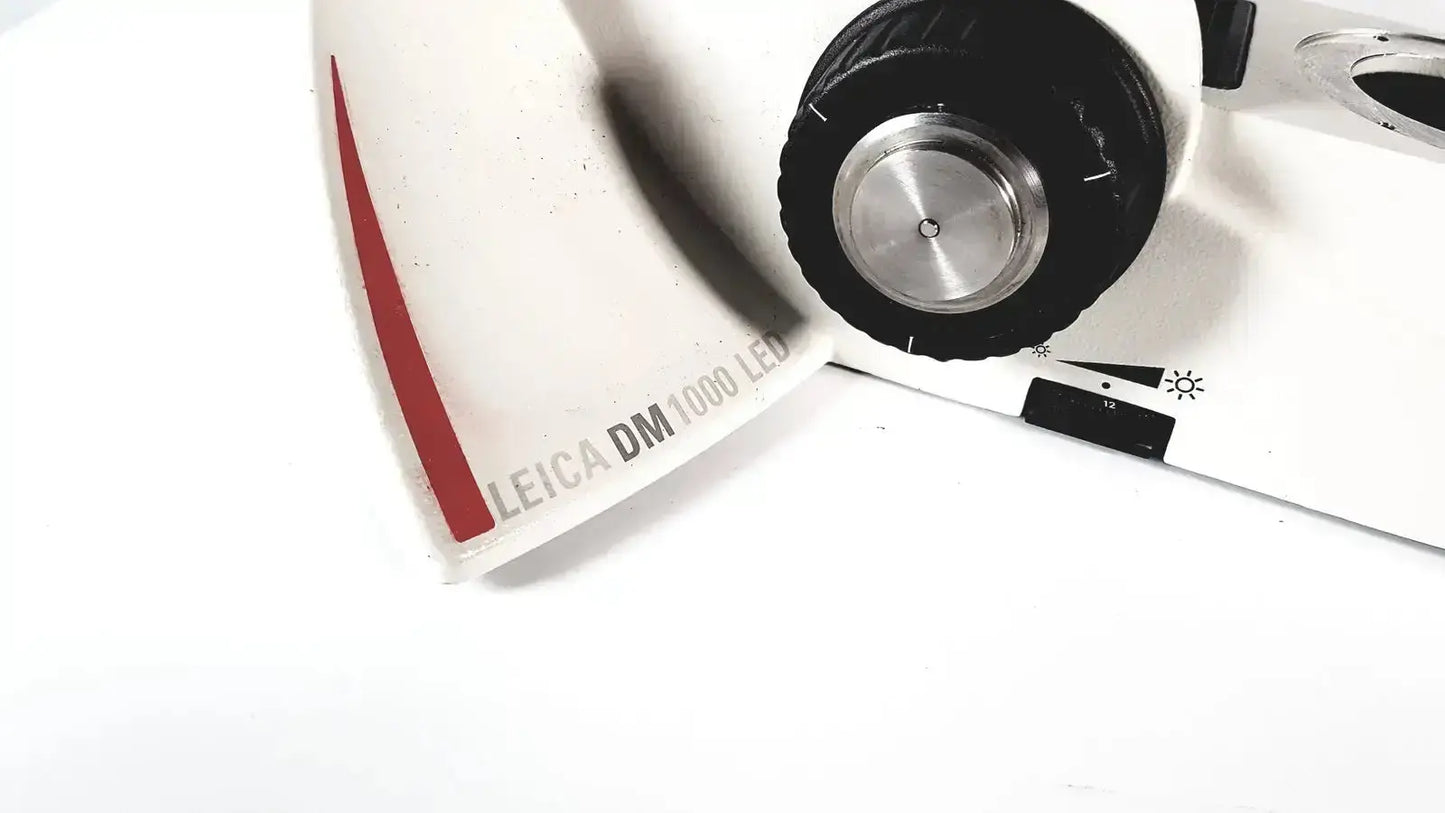 White Leica DM1000 LED microscope with red accent stripe and black focusing knob in LED microscope microsystems base