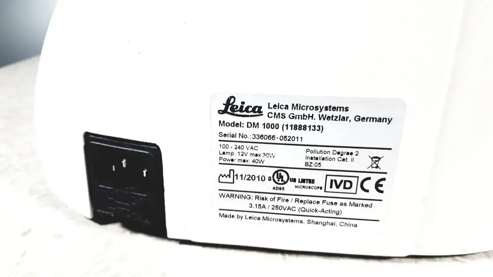 White leica dm1000 microscope base with black power plug and specifications label showing used medical equipment for sale