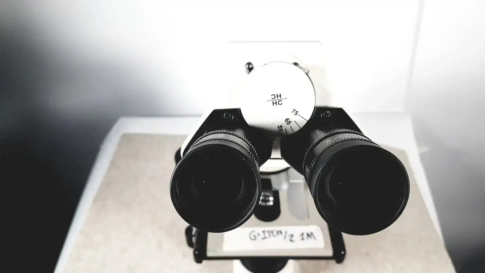 Black binoculars with white dial marked 2h hc and 75 80 mounted on stand of leica dm1000 used medical equipment for sale