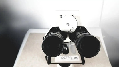 Black binoculars with white dial marked 2h hc and 75 80 mounted on stand of leica dm1000 used medical equipment for sale