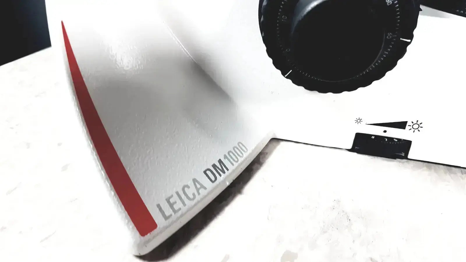 Leica dm1000 microscope with white and red body and black rotary dial pre owned medical equipment for sale