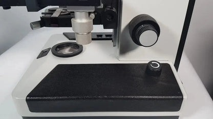 Black and silver Leitz Metallux 3 stereo zoom microscope with adjustable focus knob and stage clamp for precision viewing