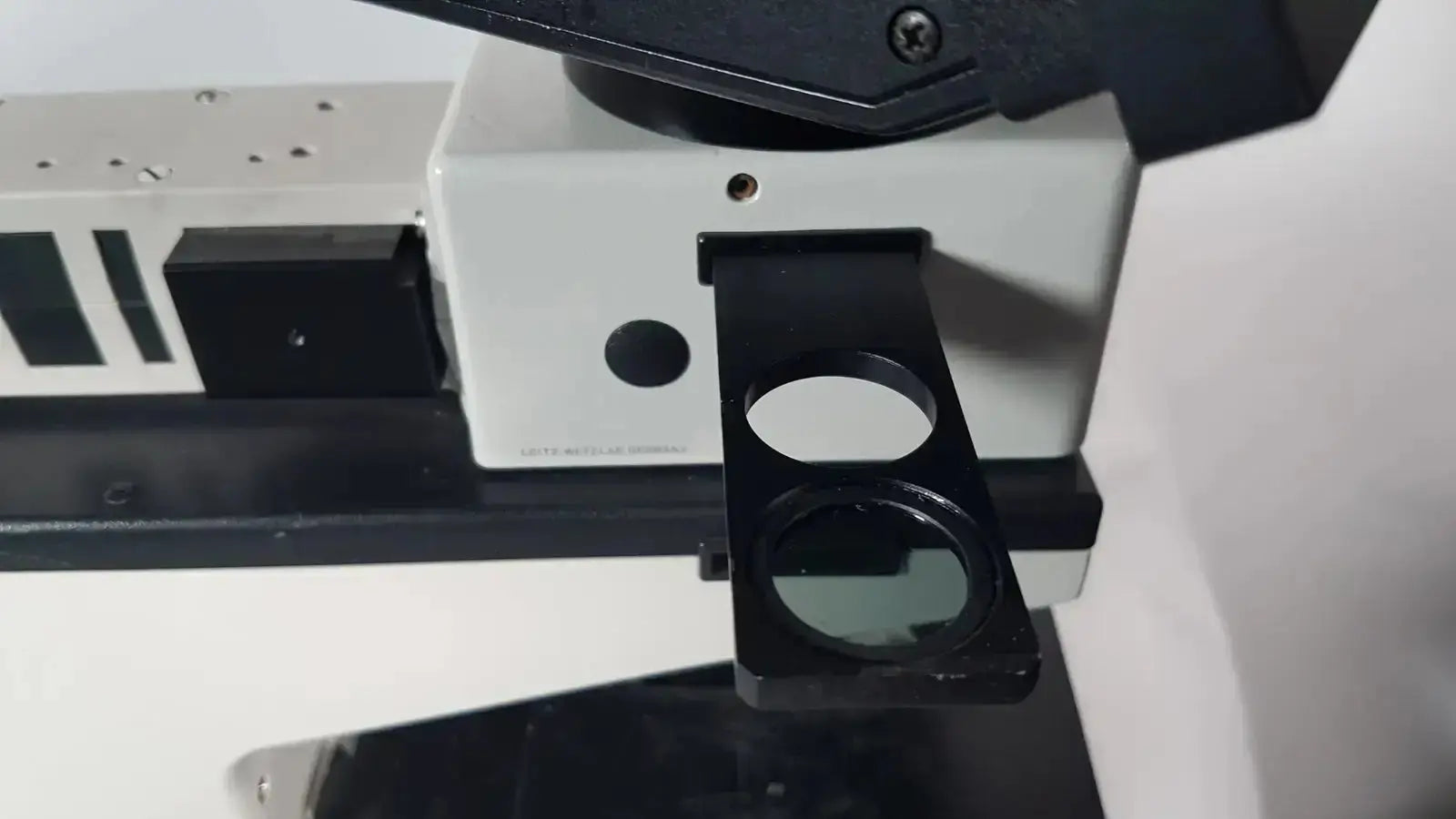 Black circular lens holder with clear glass lens attached to white and black base of leitz metallux 3 stereo zoom microscope